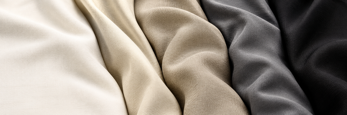 Four draped fabric swatches in cream, beige, taupe, and charcoal gray, showing soft folds and texture.