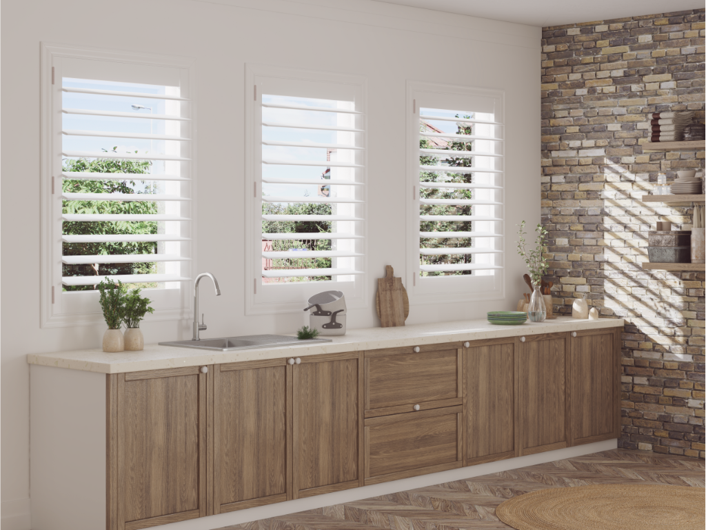 A kitchen counter with plantation shutters on the windows above it. 
