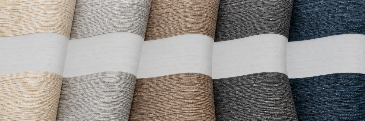A close-up of vertically stacked fabric swatches in multiple neutral and muted colors, including beige, gray, taupe, charcoal, and navy, separated by white horizontal bands.